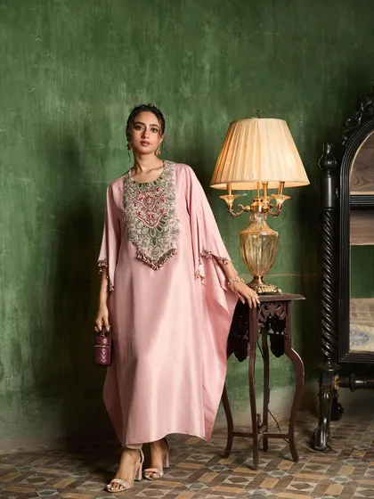 I select silhouettes that are both flowing and majestic. This soft pink kaftan, with its intricate neckline embroidery, embodies a relaxed yet sophisticated elegance for any occasion.