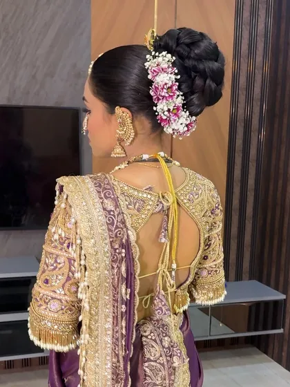 A detailed view of the back of the bride's hairstyle, featuring a braided bun with floral accessories.