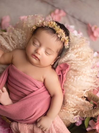 A sweet and simple pose, with the baby resting in a basket surrounded by soft pink flowers. Her peaceful expression is everything.