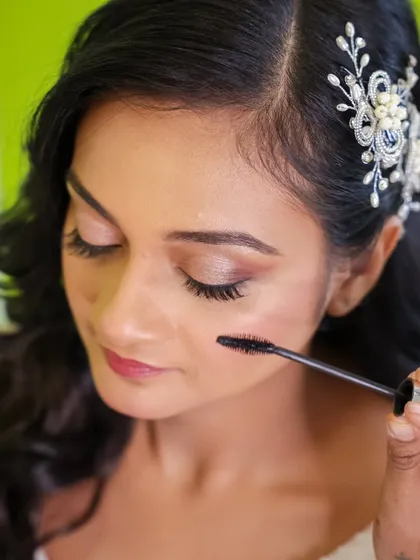 The final touches on the eye makeup. Applying mascara to the lower lashes opens up the eyes and completes the soft glam look. The delicate hairpiece adds a touch of elegance.