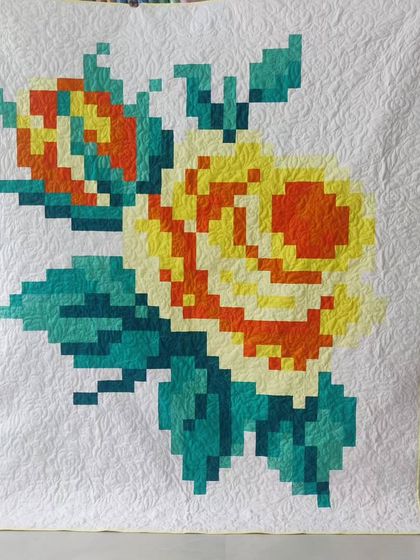 Another stunning example of a pixelated rose quilt, this one in warm shades of yellow, orange, and teal.