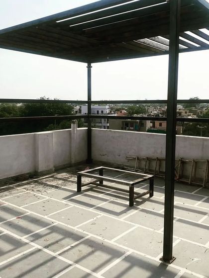 A wide shot of the installed pergola on the stone-tiled terrace.
