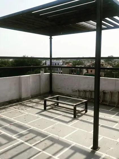 A wide shot of the installed pergola on the stone-tiled terrace.