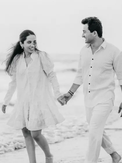 A candid black and white photo of a couple walking and laughing on the beach. This captures a genuine, joyful moment, which is at the heart of my photography style.