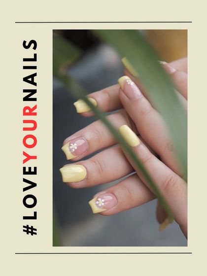 A soft yet sunny butter yellow manicure. Some nails are painted solid yellow, while others have a French tip design with a small, hand-painted daisy for a touch of detail.