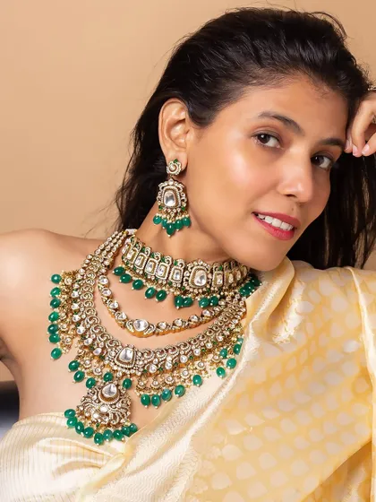 A model showcasing a layered green beaded bridal necklace set. The portrait focuses on how the jewelry sits and complements an ethnic outfit, perfect for bridal lookbooks.