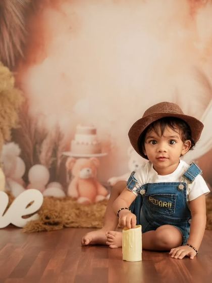 A first birthday milestone shoot with a "One" sign and a rustic, boho-themed backdrop. This studio setup is perfect for celebrating that big first year.