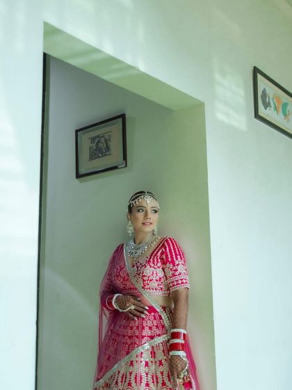 A beautiful bridal portrait taken from a doorway. The framing adds an artistic touch, capturing the bride in a moment of quiet anticipation.