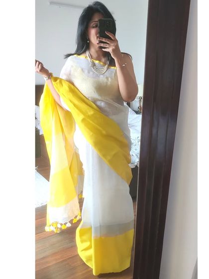 A quick mirror selfie to capture the full look before heading out. The tassels on the pallu add a playful touch to this otherwise classic white and yellow linen saree.