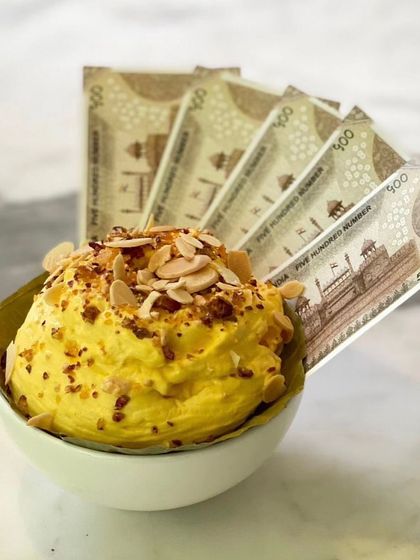 A closer look at the Daulat ki Chaat, adorned with toasted almonds and served with our signature faux currency. It's a playful nod to the dessert's origins as a 'rich man's dish'.