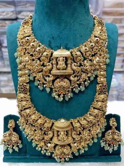 A detailed view of one of my most requested temple jewellery sets. This antique gold-plated double necklace set features intricate carvings of deities and peacocks, complete with matching jhumkas, perfect for a traditional South Indian or royal-themed wedding.