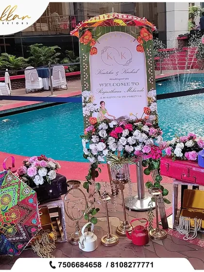 A welcome setup for a Rajasthani-themed Mehendi by the pool, featuring a custom welcome board, colorful umbrellas, painted kettles, and other traditional props.