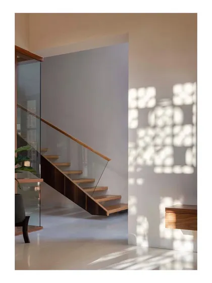 In the "Pool Court House," light filtering through a perforated screen casts dappled shadows on the wall next to a floating wooden staircase, creating a serene and poetic moment.