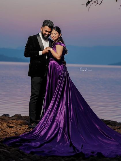 A quiet moment of connection. The rich purple satin trail gown drapes beautifully, adding a touch of luxury to this couple's serene pre-wedding photoshoot by the lake.
