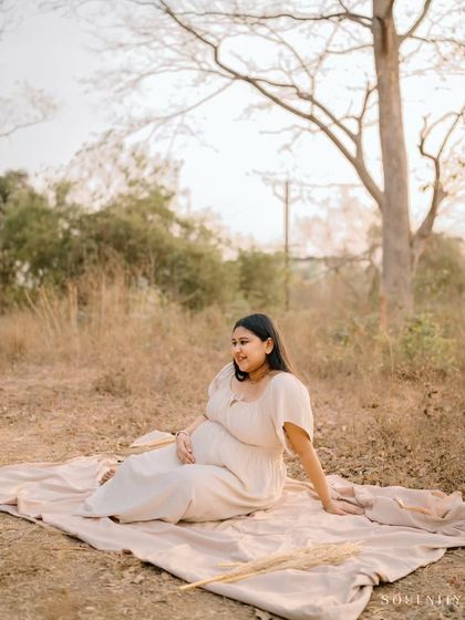 A peaceful moment in a rustic, sun-drenched field. The simplicity of the setting and the soft beige dress create a beautifully natural and earthy portrait.