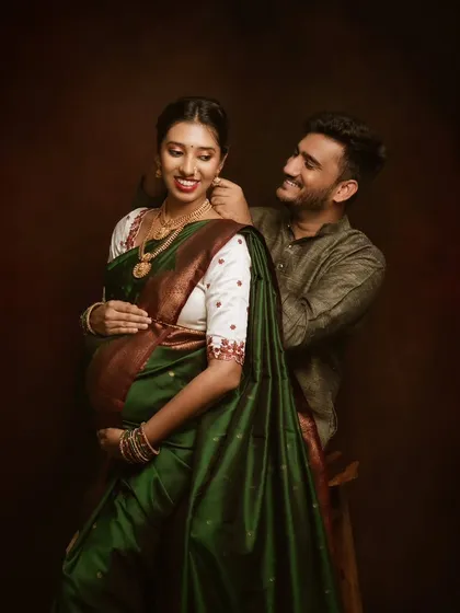 Wrapped in a gorgeous green saree, she radiates grace. This fine art portrait focuses on the beauty of traditional attire during pregnancy, with her partner's loving gesture adding a layer of intimacy.