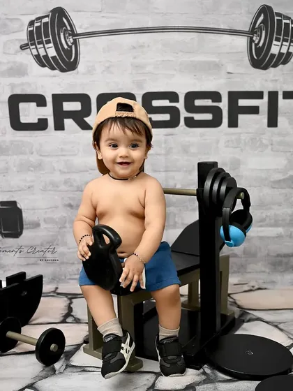 This little guy is ready for his workout! The gym-themed photoshoot is a playful and energetic option for a one-year-old's milestone session, complete with a cap and kettlebell.