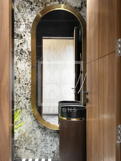 This elegant, elongated oval mirror with a thick gold frame adds a touch of vintage glamour to this powder room, complementing the dark pedestal sink and textured walls.