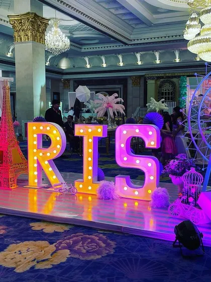 For a 'Paris' themed party, I created this spectacular installation with large marquee letters, an Eiffel Tower prop, and a Ferris wheel, all lit up to create a magical cityscape.