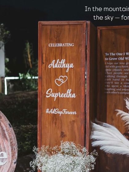 We love planning pre-wedding celebrations at stunning destinations like Wayanad. Here, the couple poses against a rustic-chic decor setup we created, with the mountains and lake providing a spectacular natural backdrop.