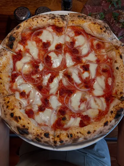 A perfect, whole Goan Sausage pizza, sliced and ready for sharing.