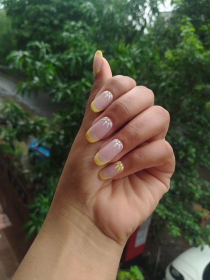 A cheerful and summery French manicure with bright yellow tips and tiny, hand-painted daisies. This is a great way to add a playful touch of art to a classic style.