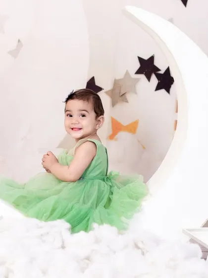 Another charming pose from the green dress moon and stars shoot, capturing the baby's sweet and playful personality.