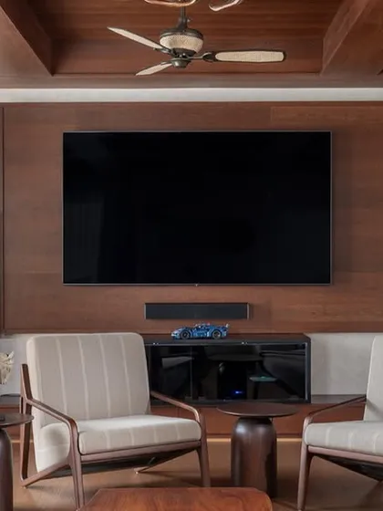This cozy den is designed for media and entertainment, featuring a rich wood-paneled wall and a coffered ceiling. It opens onto a terrace, offering a perfect retreat for intimate gatherings.