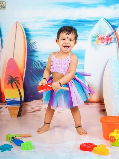 This little beachgoer is ready for fun with her bucket and spade. The colorful tutu adds a touch of whimsy to the scene.