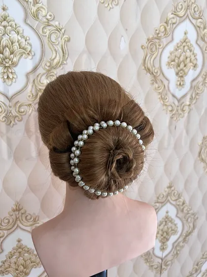 A classic rose bun, elegantly framed with a string of pearls. This is a timeless hairstyle for brides and is a key part of our bridal hairstyling course.