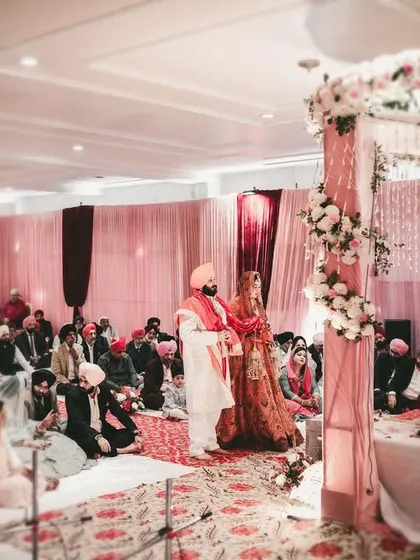 A wide shot of the Anand Karaj ceremony, showing the couple and their guests.
