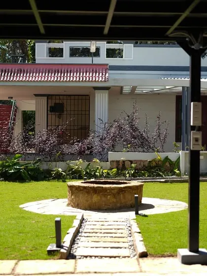 Viewed from under a pergola, the stone well acts as a central anchor for the entire backyard design.