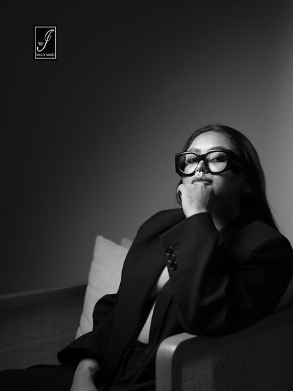 A black and white version of the same series, with the model in a relaxed, seated pose, creating a moody and atmospheric feel.