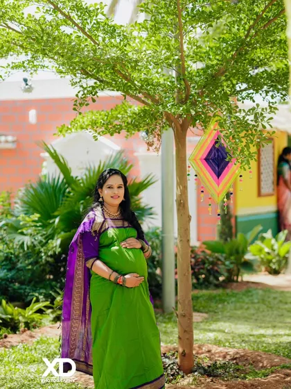 A solo portrait of the mother-to-be in a colorful garden, holding her baby bump.