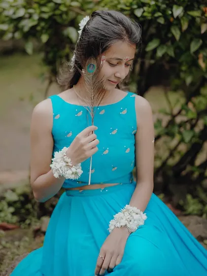 A quiet moment of reflection, as the model portraying Radha gently holds a peacock feather, a symbol of Lord Krishna.