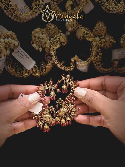 This pair of earcuffs features a beautiful design with ruby-colored stones and small bell drops, offering a royal and traditional look.