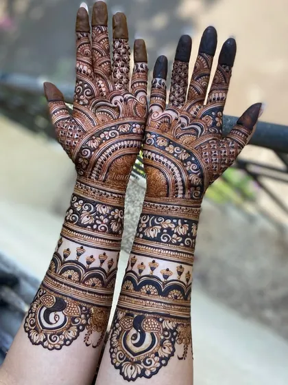 This engagement mehendi features graceful peacock motifs at the wrist, surrounded by intricate floral and geometric patterns.