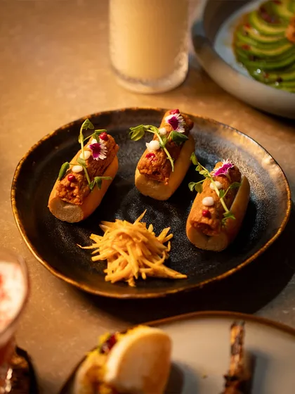 A closer look at one of my signature small plates. The textures of the filling, the soft bun, and the crisp garnish of fried ginger create a complete, multi-layered bite.