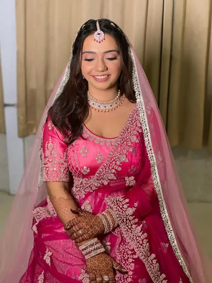 The smile of a happy bride. Her makeup is soft and natural, and her simple hairstyle lets her radiant happiness and beautiful pink lehenga be the focus.