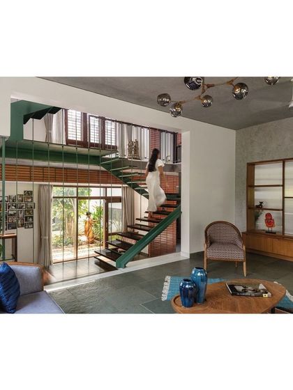 A view from the living area looking up at the floating steel staircase. This open-plan design uses double-height volumes to visually connect different levels of the home, creating a sense of spaciousness and allowing light to penetrate deep into the floor plan.