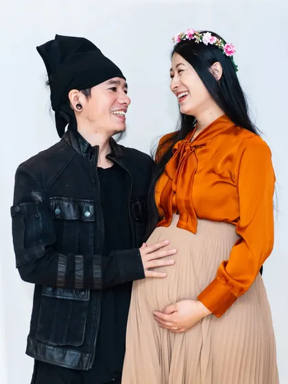Laughter and love in the studio. This candid shot captures a genuine, happy moment between the expecting couple.