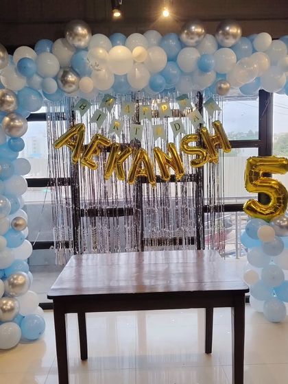 A balloon frame in light blue, white, and silver for a 5th birthday party.