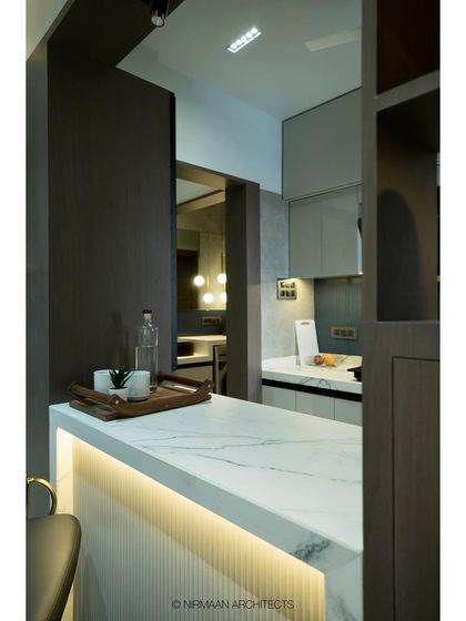 The breakfast counter at Tulsi Heights is finished with white marble and fluted tiles, serving as a stylish centerpiece that connects the kitchen and living areas.