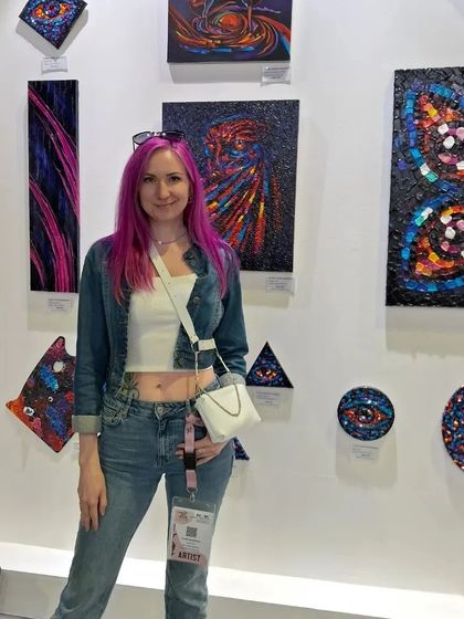 The artist behind 'Symbolographie' stands with her unique, symbolic artworks at World Art Dubai. Her distinctive style was a highlight of the show.