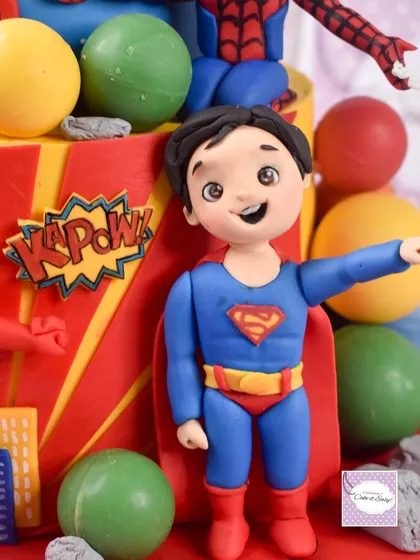 A detailed look at the Superman figurine, complete with his iconic cape and pose, surrounded by hand-painted "KAPOW!" speech bubbles.