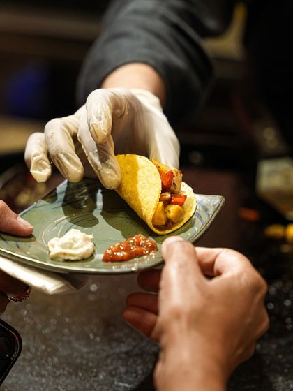 A freshly assembled taco being passed to a guest, showcasing the interactive and personalized nature of our live food stations.