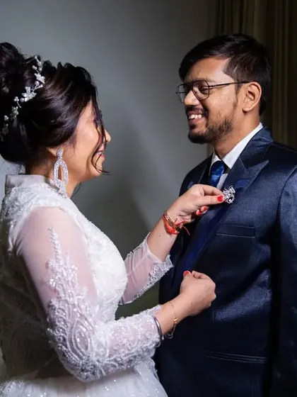 A candid moment of the bride helping the groom with his boutonnière, a small gesture of love and care.