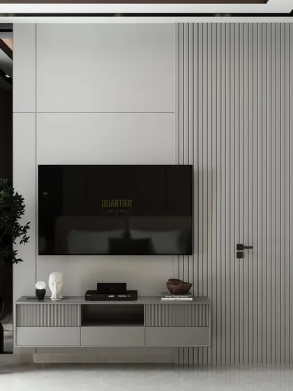 A guest bedroom design for Apex D'Rio featuring a feature wall with intricate mouldings and quilting, accented with gold strips. The TV unit on the opposite wall has a door flushed into the paneling for a seamless look.