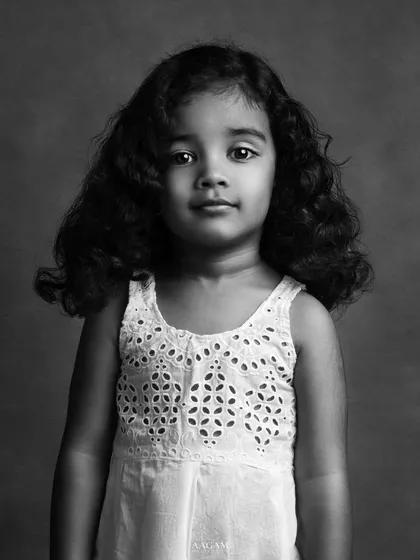 A simple and beautiful black and white portrait of a little girl. Her direct gaze and the delicate details of her dress create a timeless and innocent image.