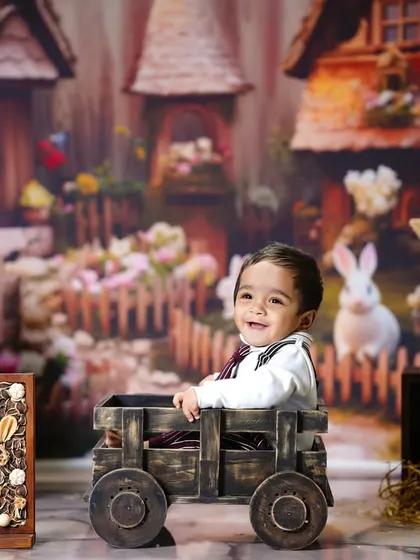 A happy smile from our little bunny as he sits in a wooden cart, surrounded by Easter eggs and rabbit friends.